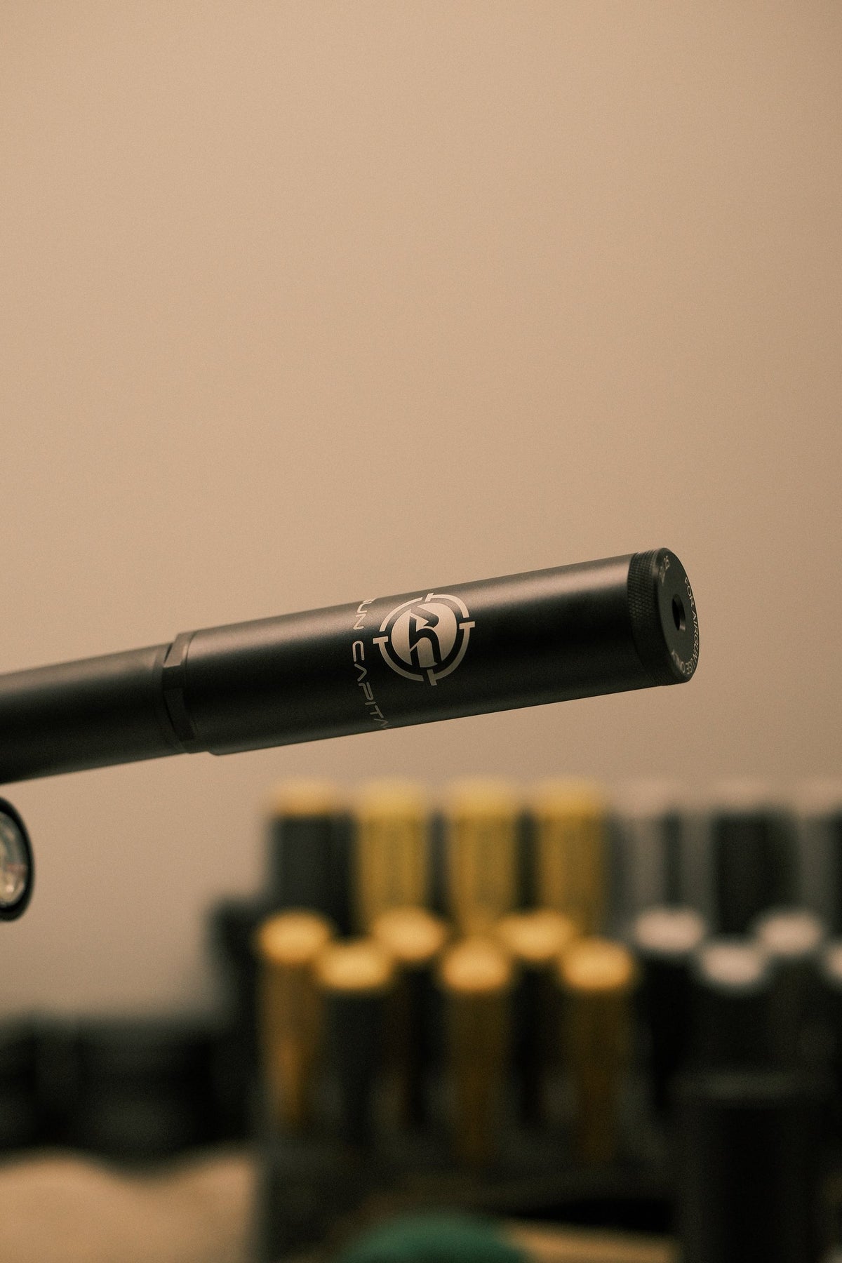 Airgun suppressor on a rifle barrel above rows of pellet tins