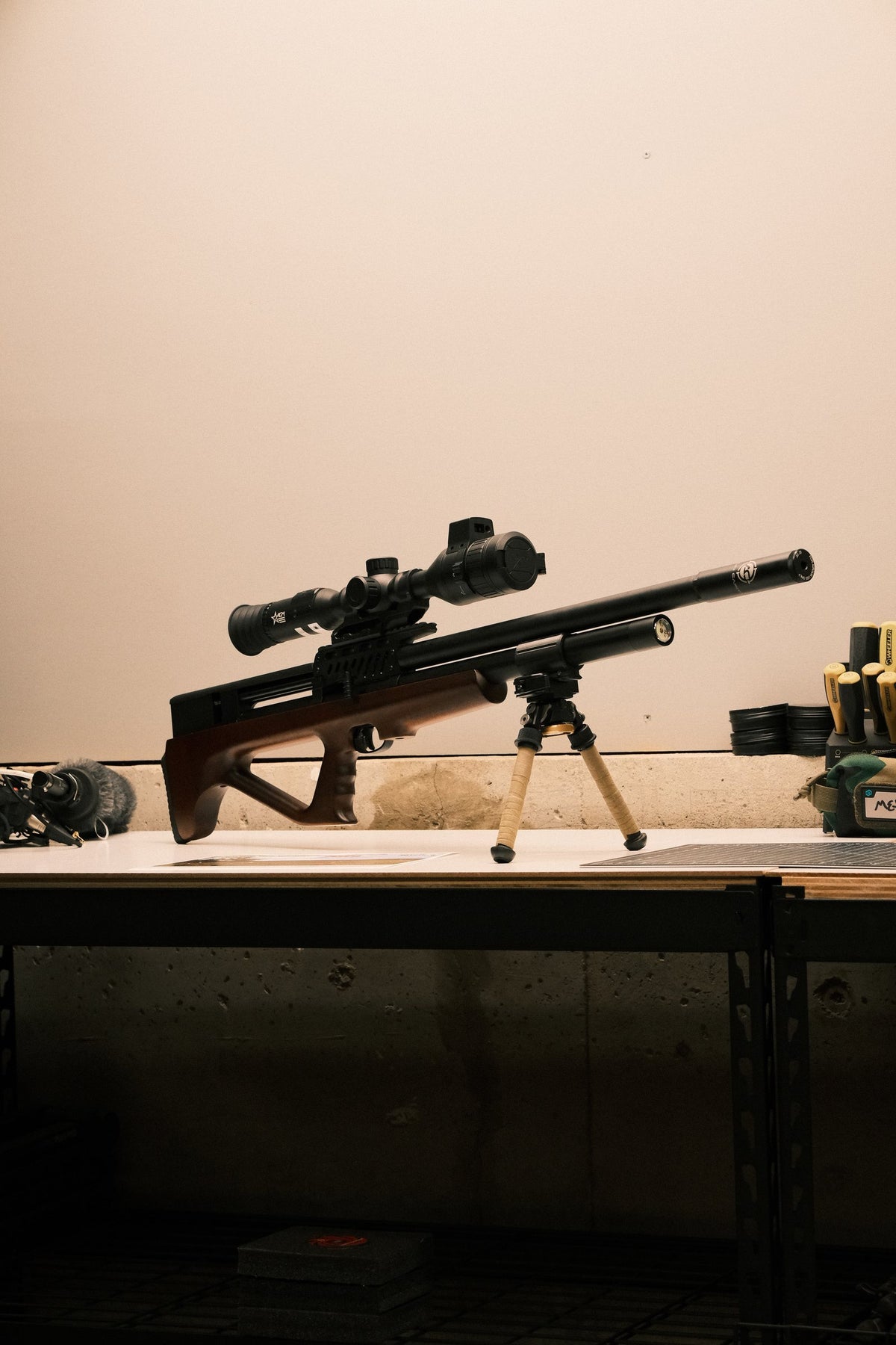 Bullpup PCP air rifle with scope and suppressor on a workbench