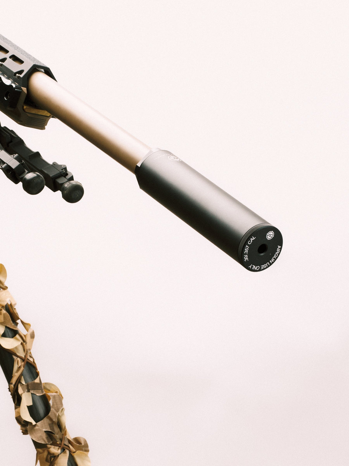 Airgun suppressor on a tan air rifle barrel, close-up
