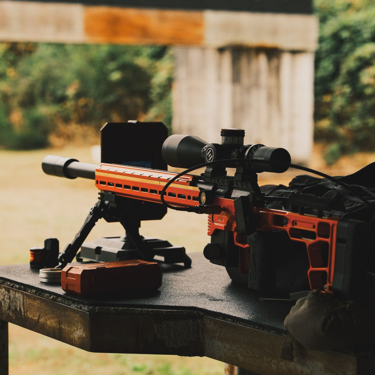 Orange FX air rifle with an Airgun Capital suppressor on a range bench