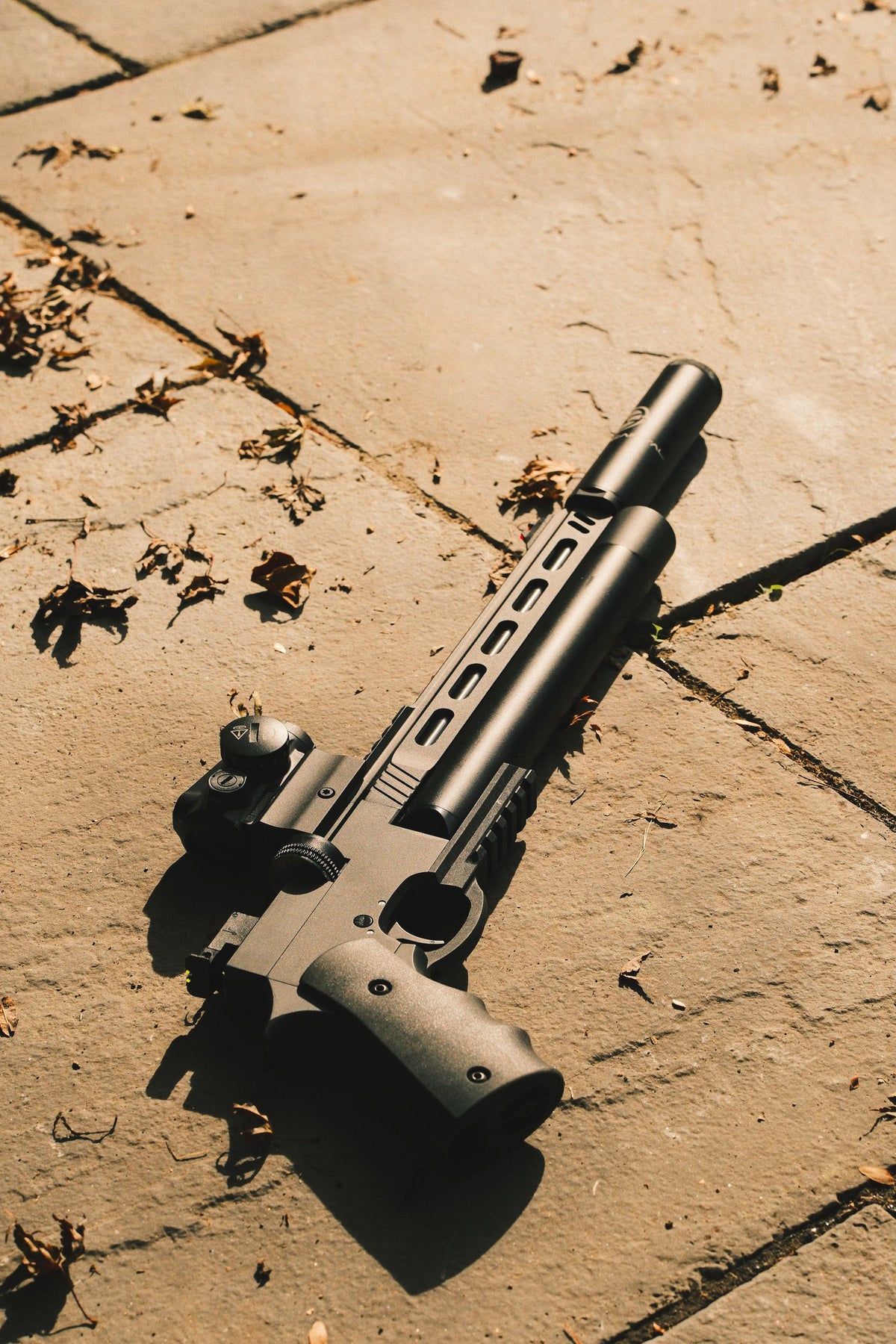 Suppressed air pistol lying on stone paving